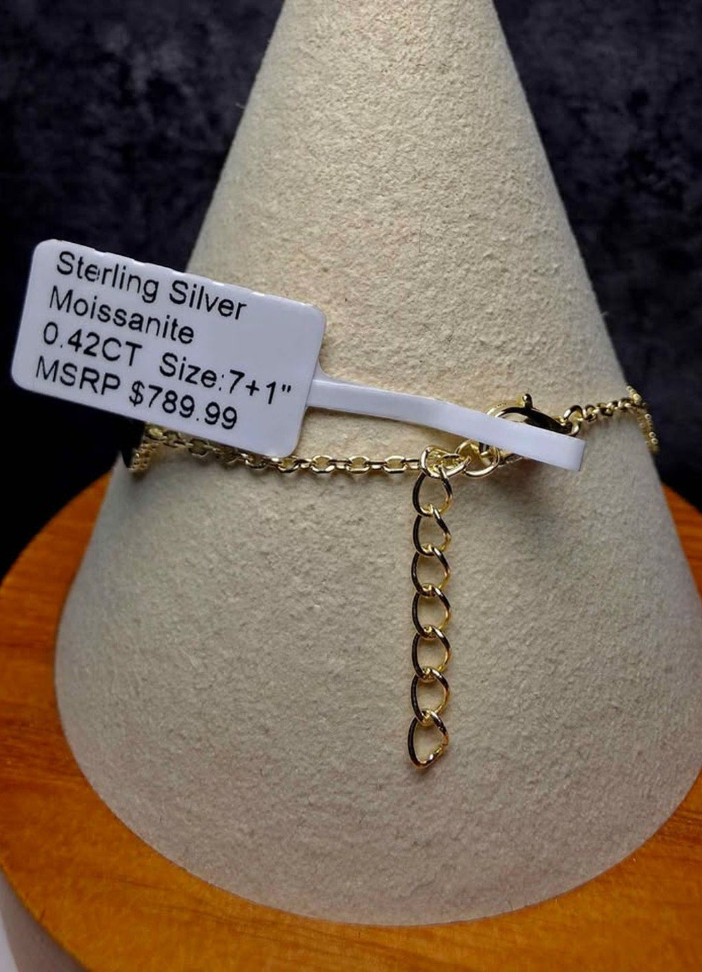A sterling silver and moissanite chain bracelet displayed on a textured cone stand, with a white price tag attached.