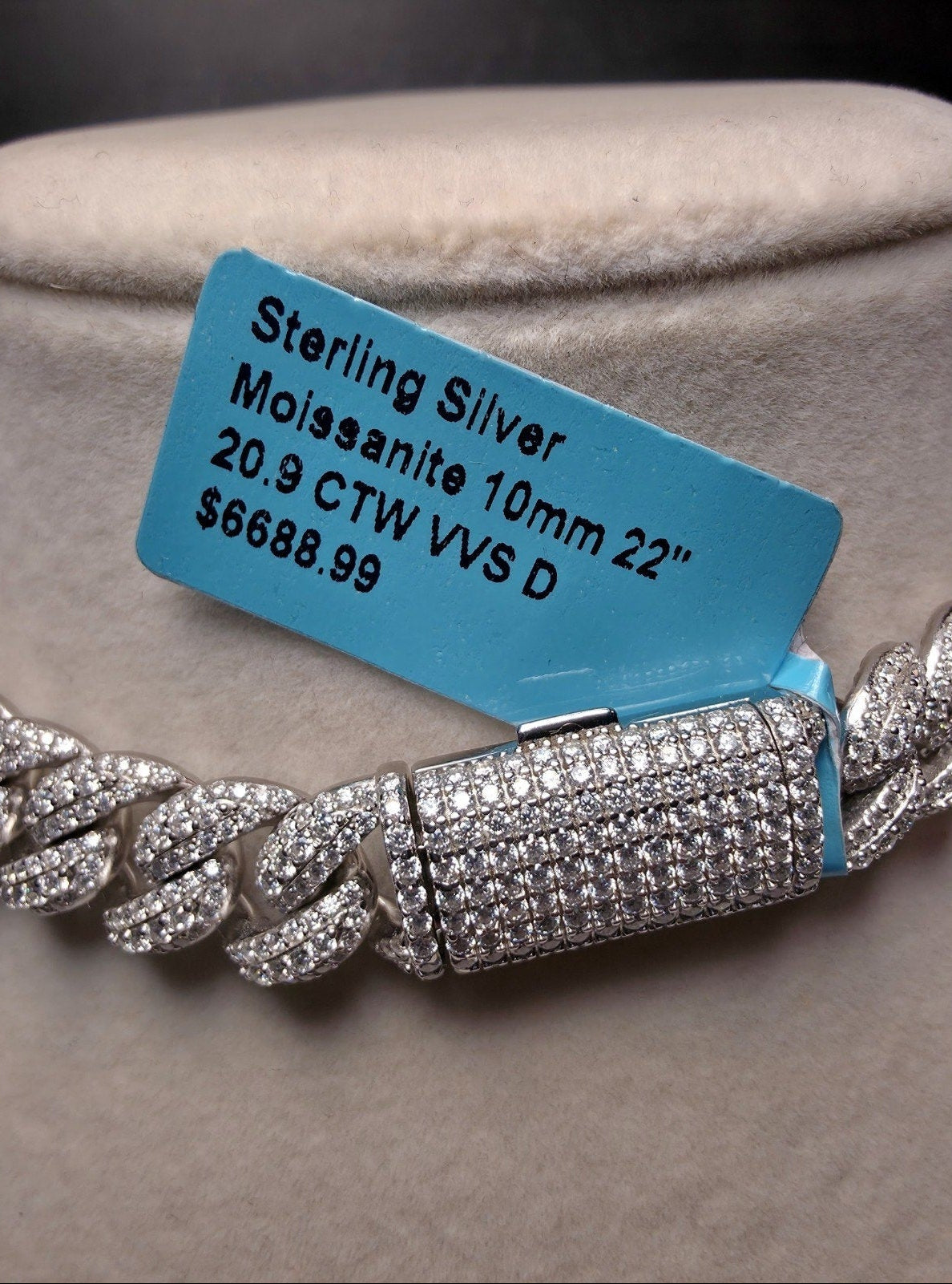 Sterling silver moissanite chain bracelet displayed on a beige jewelry stand, with a blue price tag attached. The tag reads 'Sterling Silver Moissanite 10mm 22" 20.