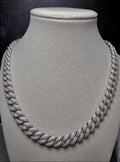 A thick silver Cuban link chain necklace, heavily embellished with small clear stones, displayed on a textured light gray velvet jewelry bust against a dark background.